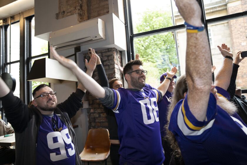 Supporters of the the The Minnesota Vikings team cheer at a fan interaction event at The Brotherhood Of Pursuits And Pastimes sports bar in Manchester, England, Wednesday, Sept. 28, 2022. A half-dozen NFL teams are aggressively targeting fans in Britain now that they have new marketing rights in the country. They’re signing commercial deals and hiring local media personalities in bids to expand their fanbases and tap international revenue. (AP Photo/Jon Super)