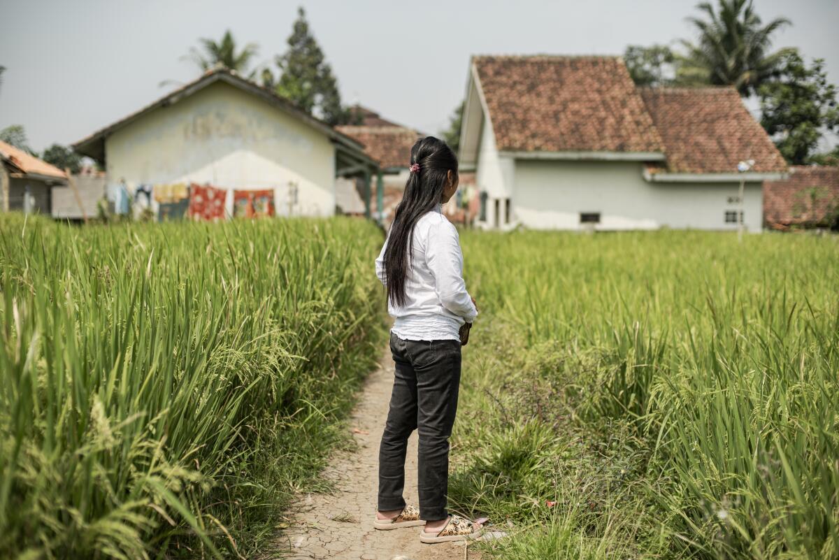 A photo of a woman standing on a dirt path at a resort in Indonesia.