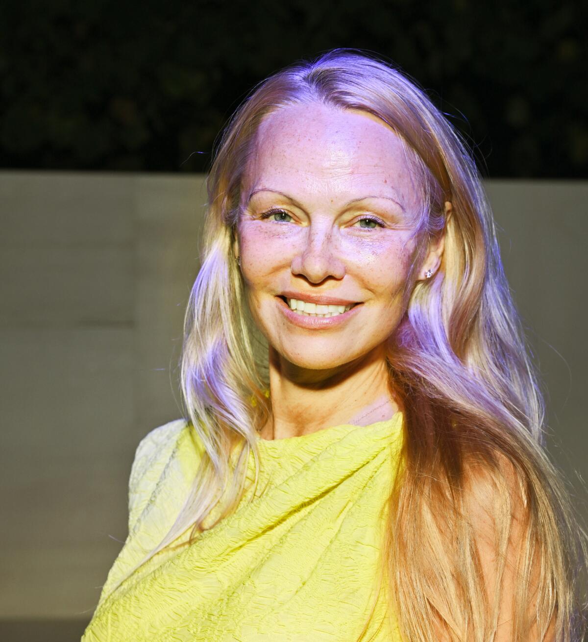 A woman with long blond hair, without makeup, in a yellow dress.