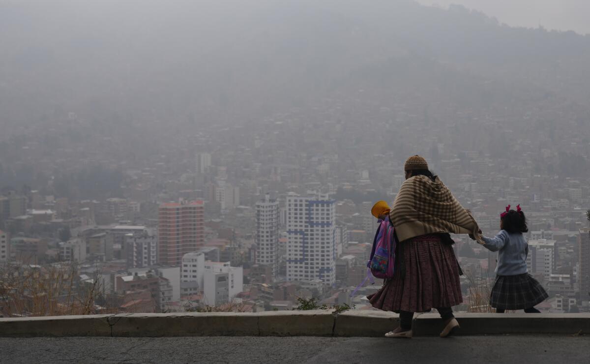 Una mujer acompaña a su hija a la escuela en medio del humo de los incendios 