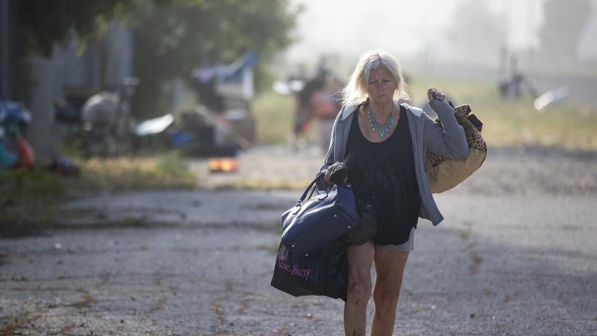 Donna Nycz, 62, carries some of her belongings after being ordered out of an encampment east of De Soto Avenue along the Metrolink route in Chatsworth last month.