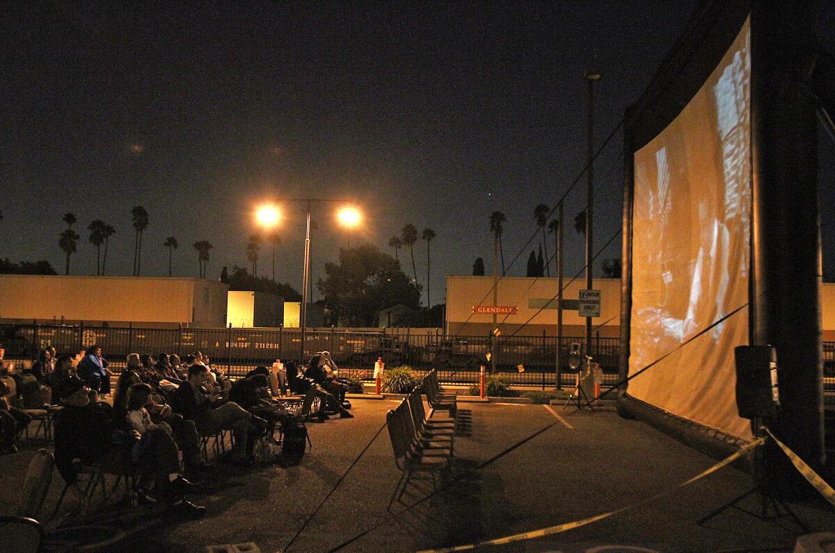 Community members watch Billy Wilder's film noir classic "Double Indemnity" as well as they can despite the light interference from the parking lot at the Glendale Metrolink Station on Thursday, Oct. 3, 2013. Glendale'sCommunity Development Department hosted a scavenger hunt, brought in food trucks, and screened the movie for the community in an effort to bring attention to the station and the area.