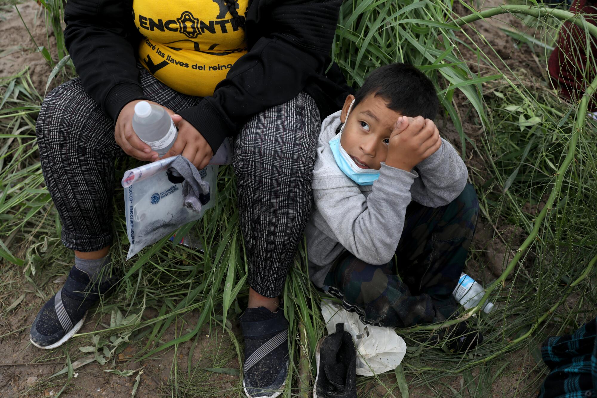 A boy seated next to his mother looks up. 