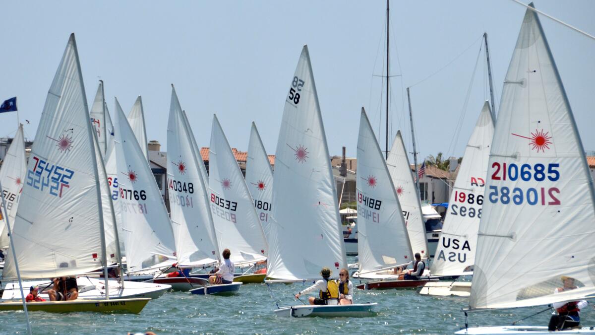 Lasers navigate into position at the start line of Flight of Newport Beach sailboat race in Newport Harbor on Sunday.