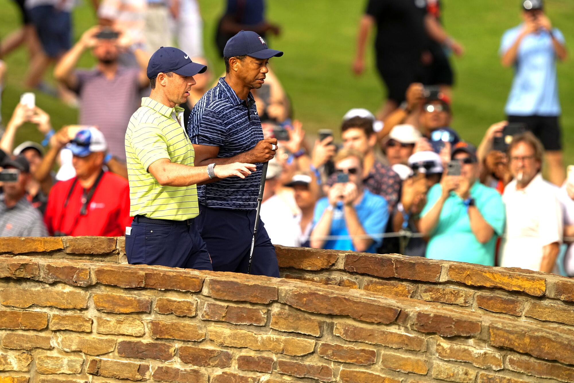 Tiger Woods and Rory McIlroy walk on the 13th hole during the first round of the PGA Championship in Tulsa, Okla.