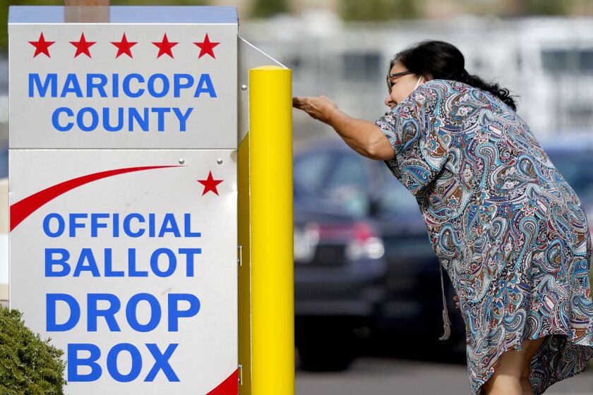 FILE - A voter drops off her ballot at a drop box, Nov. 7, 2022, in Mesa, Ariz. Fears of aggressive poll watchers sowing chaos at polling stations or conservative groups trying to intimidate votes didn't materialize on Election Day as many election officials and voting rights experts had feared. Voting proceeded smoothly across most of the U.S., with a few exceptions of scattered disruptions. (AP Photo/Matt York, File)