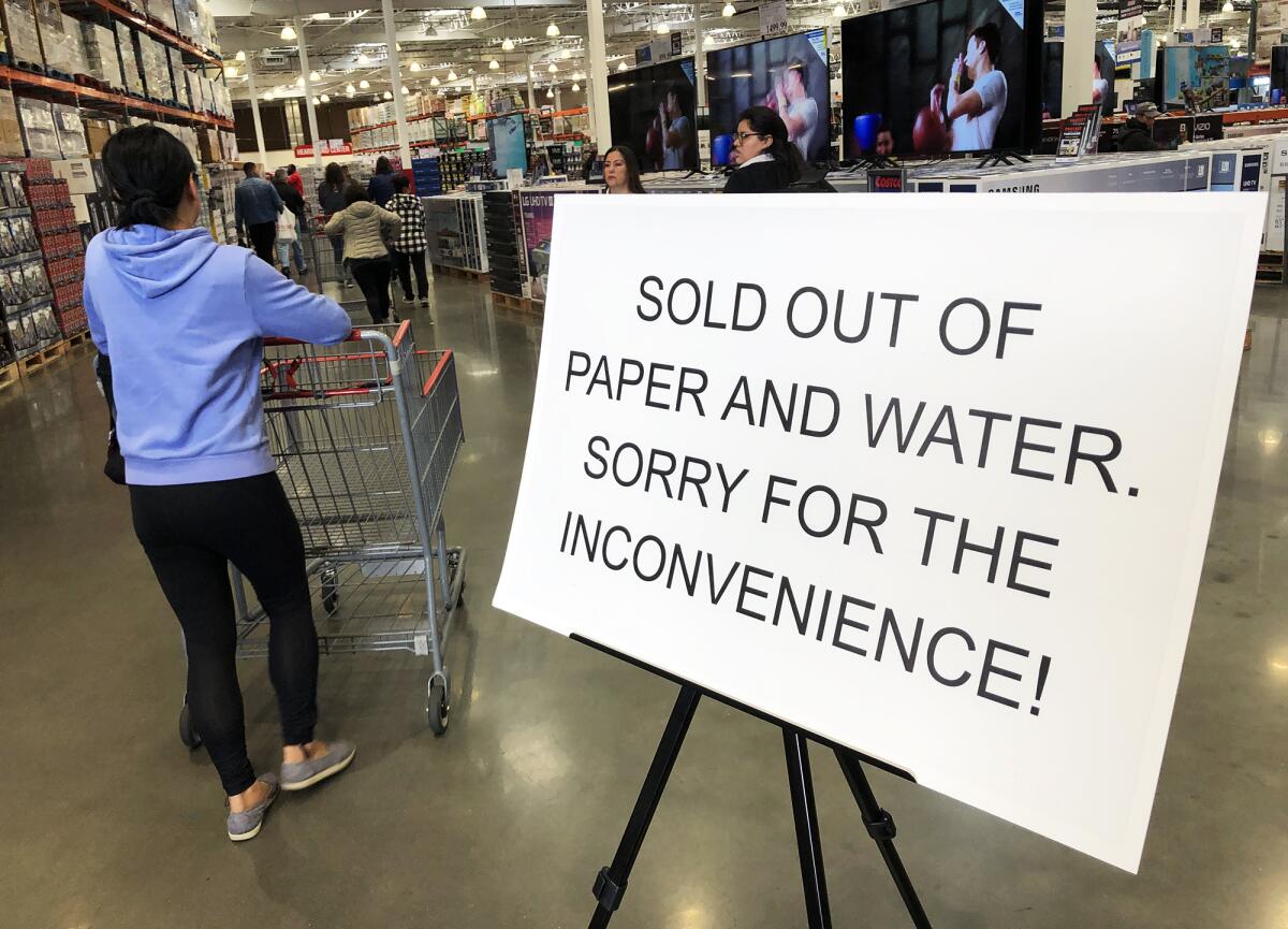 A sign in Costco in Huntington Beach tells customers Monday that the store is out of water and paper products as people stockpile those and other items as a response to the coronavirus outbreak.