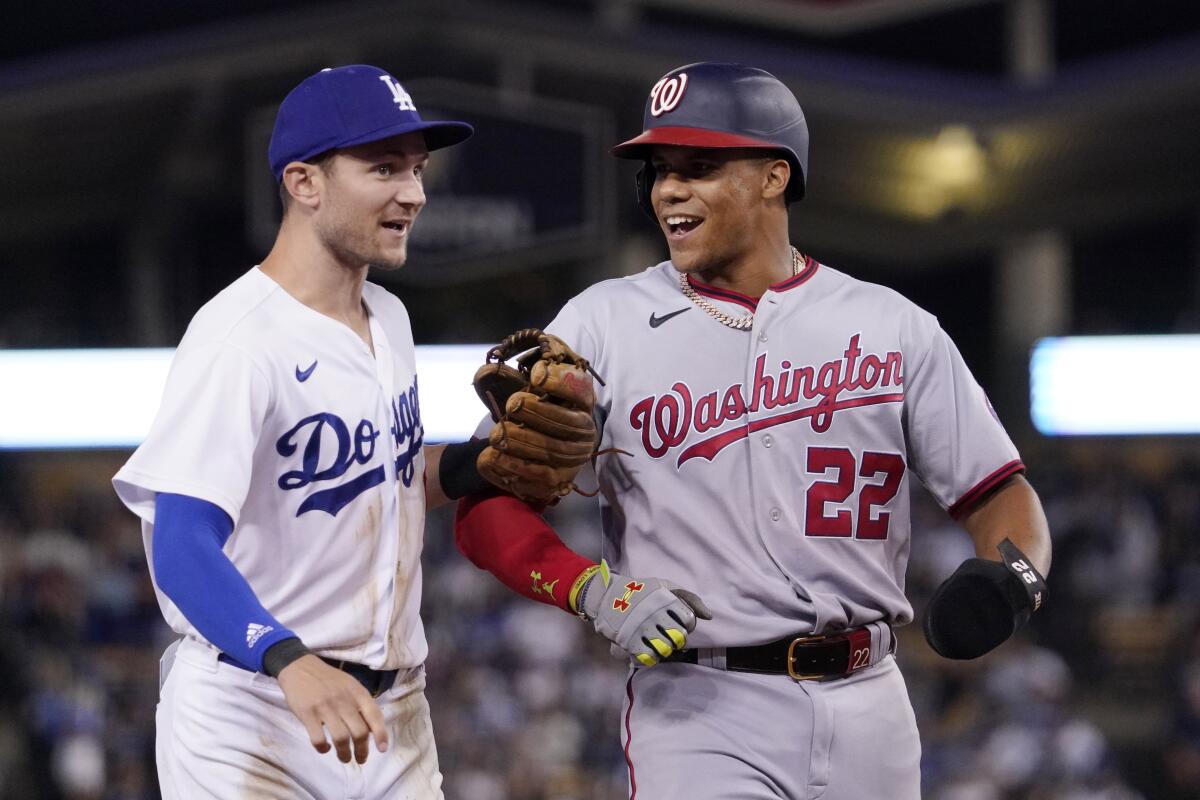 Dodgers' Trea Turner and Washington Nationals' Juan Soto joke around during a game.