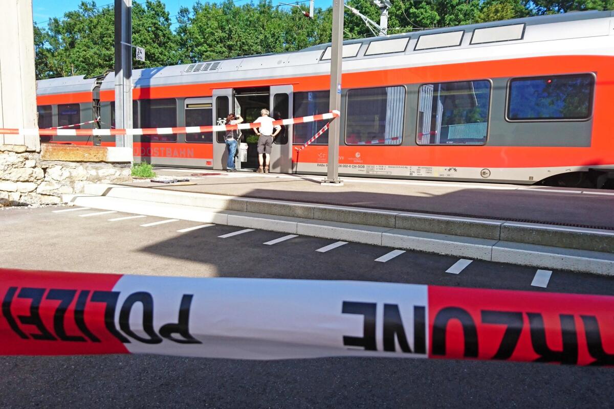 Police officers stand by a train at the station in Salez in eastern Switzerland after a man set a fire and stabbed passengers on Aug. 13.