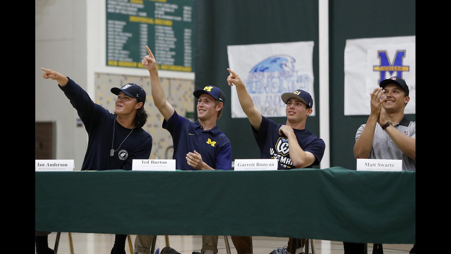 Athletes, left to right, Ian Anderson, Ted Burton, Garrett Runyan and Matt Swartz point to friends in the bleachers during a signing day ceremony at Edison High on Thursday.