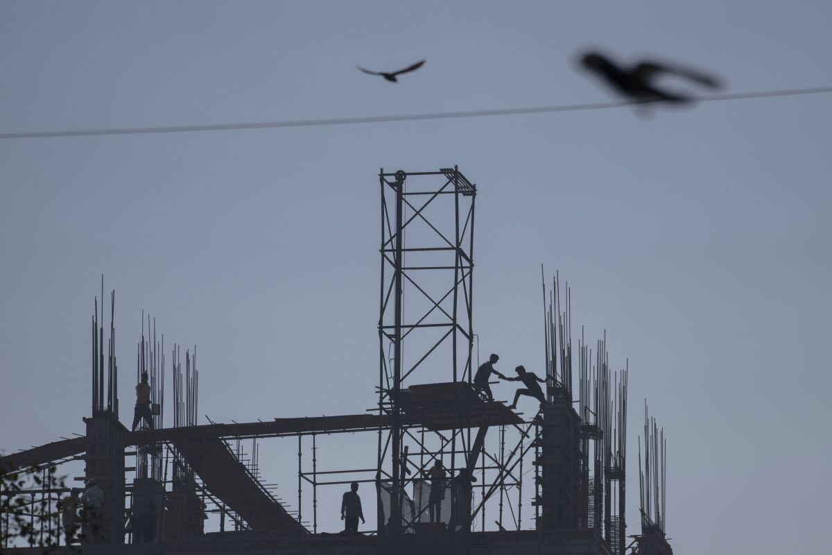 Indian daily wage laborers work at buildings under construction in Mumbai, India, Tuesday, Feb. 1, 2022. Indian Prime Minister Narendra Modi's government on Tuesday announced a series of investments to shore up spending in infrastructure projects in its annual budget designed to spur growth and popularity just days ahead of key state elections. (AP Photo/Rafiq Maqbool)
