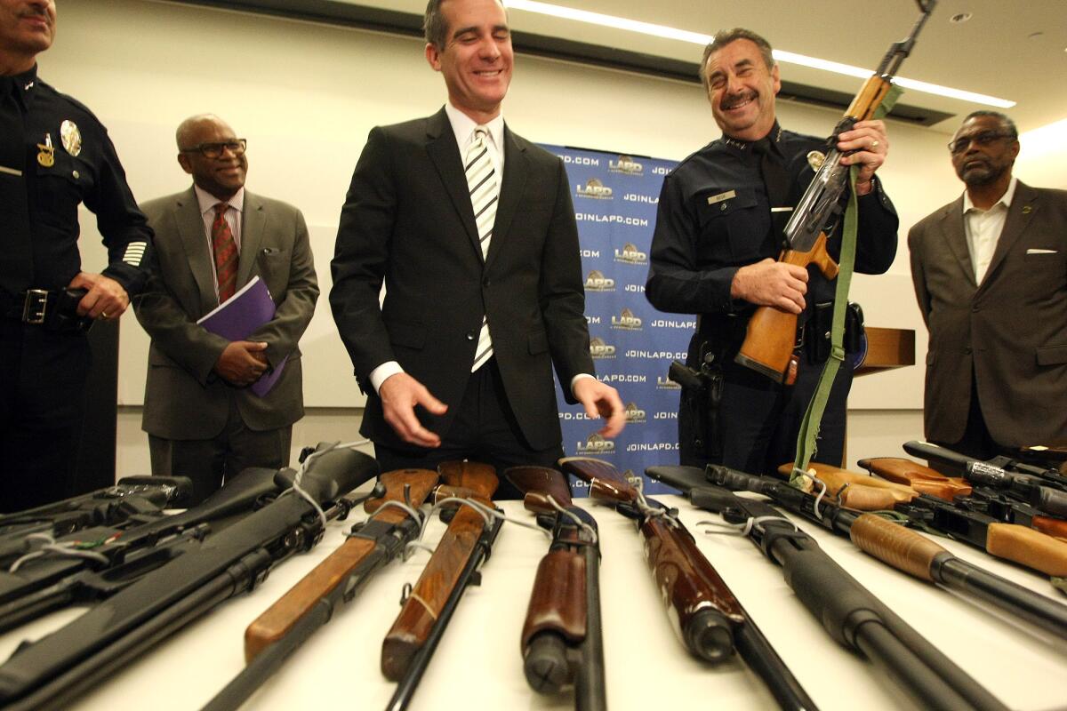 LAPD Chief Charlie Beck holds an AK-47 assault rifle standing alongside Los Angeles Mayor Eric Garcetti as they discuss the results of the city's gun buyback program.