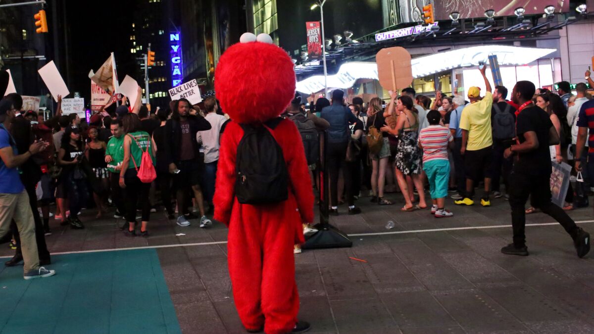 Costumed characters watch activists protest in Times Square.