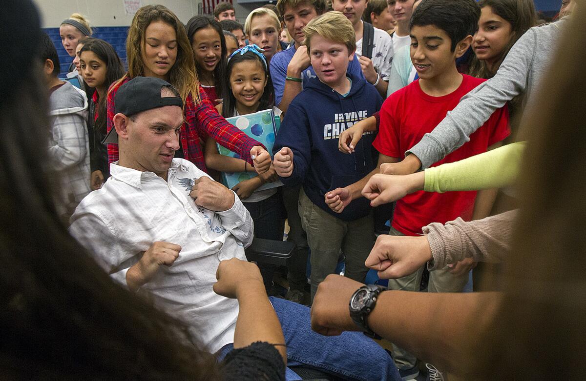 Aaron Rubin, 31, who overdosed from prescription drugs and suffered catastrophic brain damage when he was 23, bumps fists with middle school students at the Corona Del Mar High School gym on Thursday. Rubin and his mother and father Sherrie and Michael Rubin talked to the students about the dangers of using drugs.