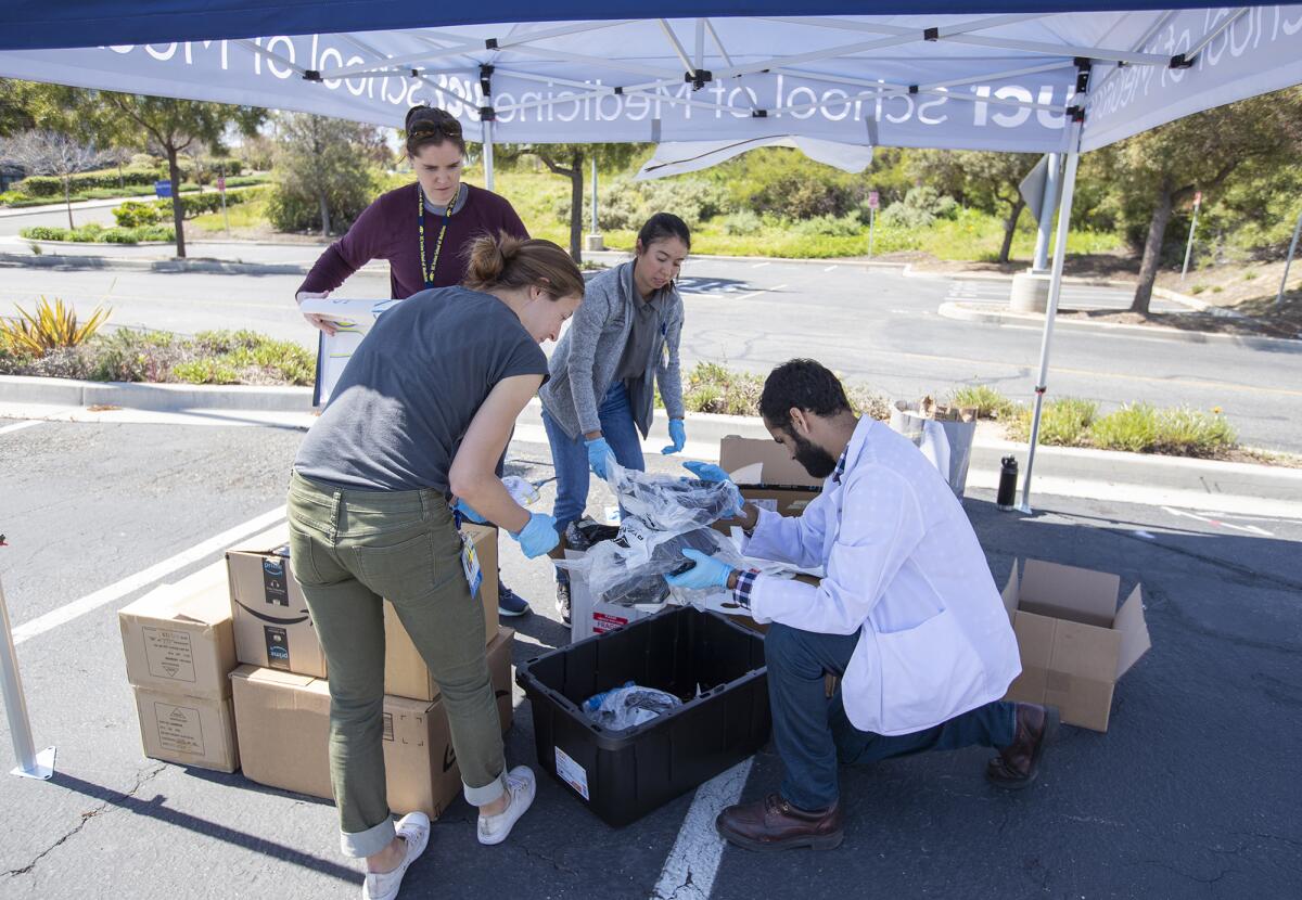 UC Irvine medical students, clockwise from front, Alexandra Bray, Jessica Sea, Catriona Lewis and Jaspal Bassi organize personal protective equipment such as masks, sanitizer, gloves and other supplies donated for medical workers Monday during a collection in Irvine.