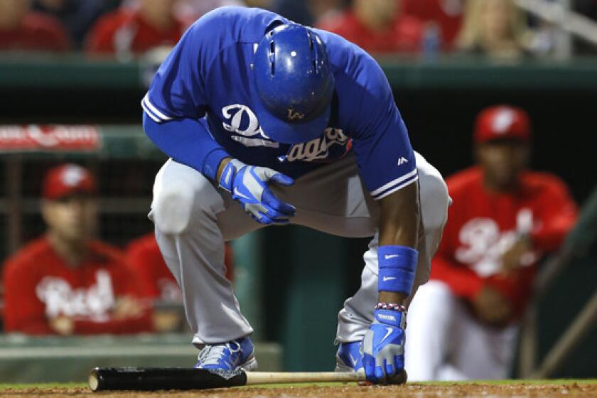 Dodgers right fielder Yasiel Puig goes to pick up his bat during the fourth inning of Wednesday's exhibition game against the Cincinnati Reds. Puig left the game after two at-bats because inflammation in his back.