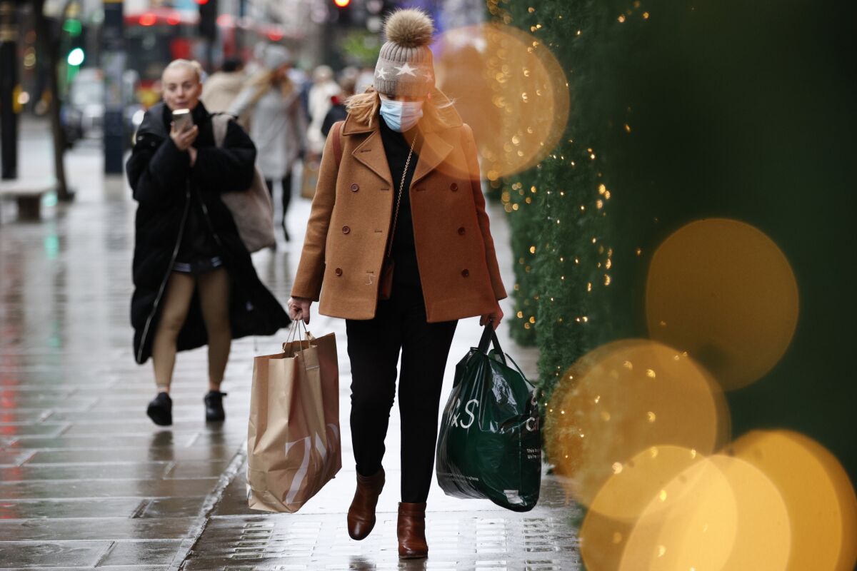 A woman wearing a face mask carries bags of shopping along Oxford Street in London
