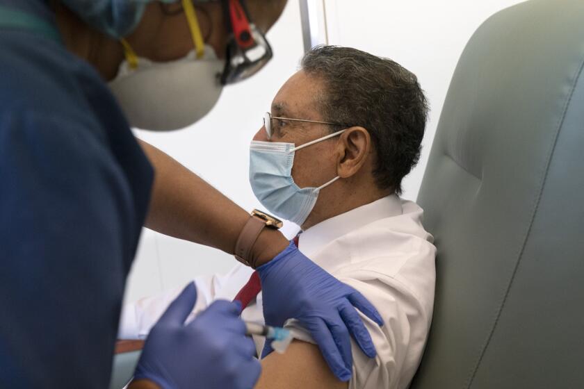 In this Wednesday, Feb. 10, 2021, photo Wallace Charles Smith, 72, who is a pastor at Shiloh Baptist Church, receives his first COVID-19 vaccination by nurse Michelle Martin, at United Medical Center in southeast Washington. (AP Photo/Jacquelyn Martin)