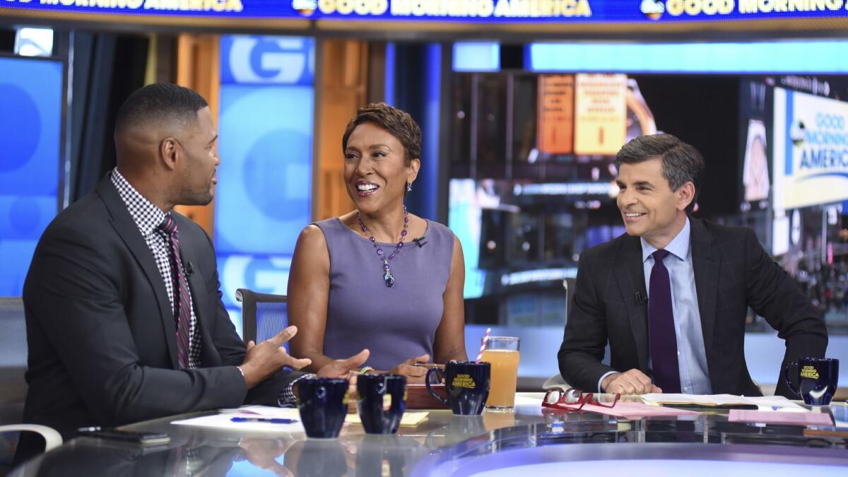 Co-anchors Michael Strahan, left, Robin Roberts and George Stephanopoulos on the set of "Good Morning America" in New York. The show is expanding to a third hour in September.