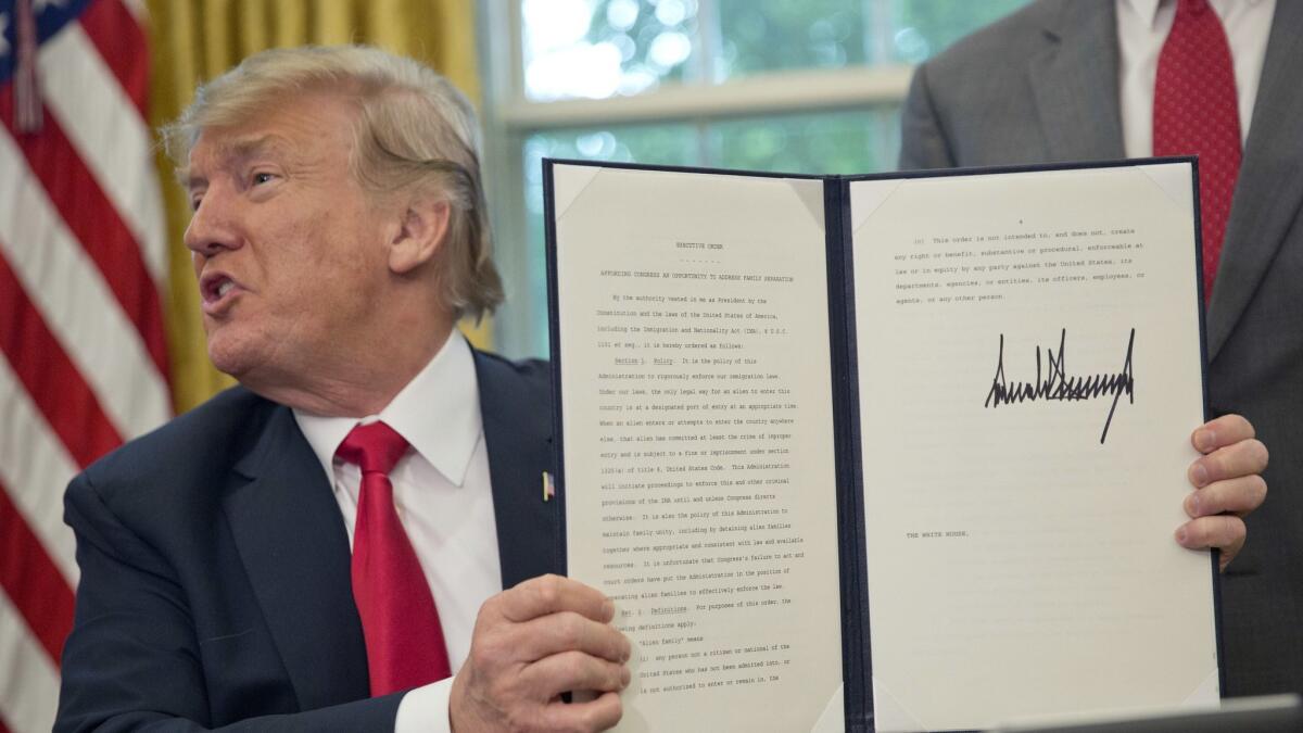 President Trump holds up the executive order he signed to end family separations at the border.