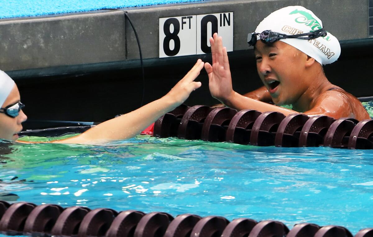Costa Mesa's Melanie Pang high-fives an opponent after winning the Division 3 girls' breaststroke on Friday.