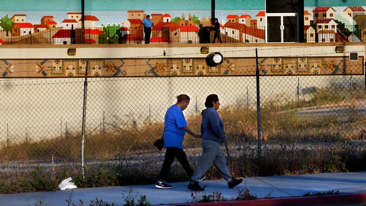 Pedestrians walk along Lorena Street near 1st Street in Boyle Heights, past an empty lot where a housing development for homeless and low-income people may be built.