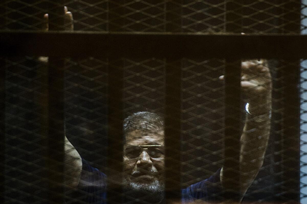 Mohamed Morsi gestures from the defendants cage as he attends his trial at the police academy on the outskirts of Cairo on June 2.