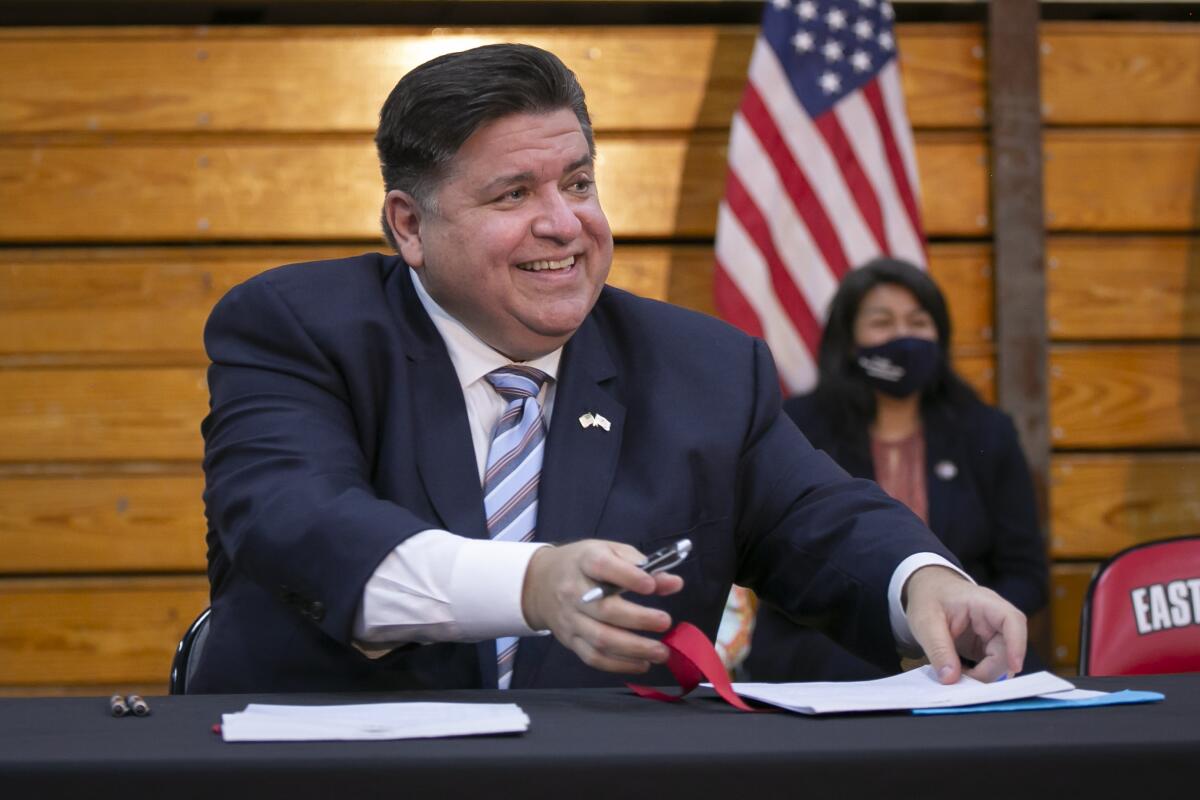 Illinois Gov. J.B. Pritzker smiles while signing legislation that expands protections for immigrant and refugee communities at East Aurora High School in Aurora, Ill. Monday, Aug. 2, 2021. (Rich Hein/Chicago Sun-Times via AP)