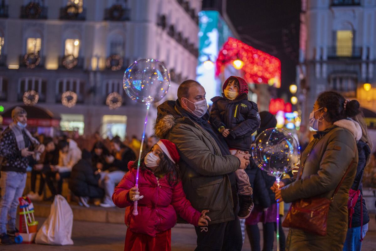 A family wearing masks on a crowded street at night in downtown Madrid