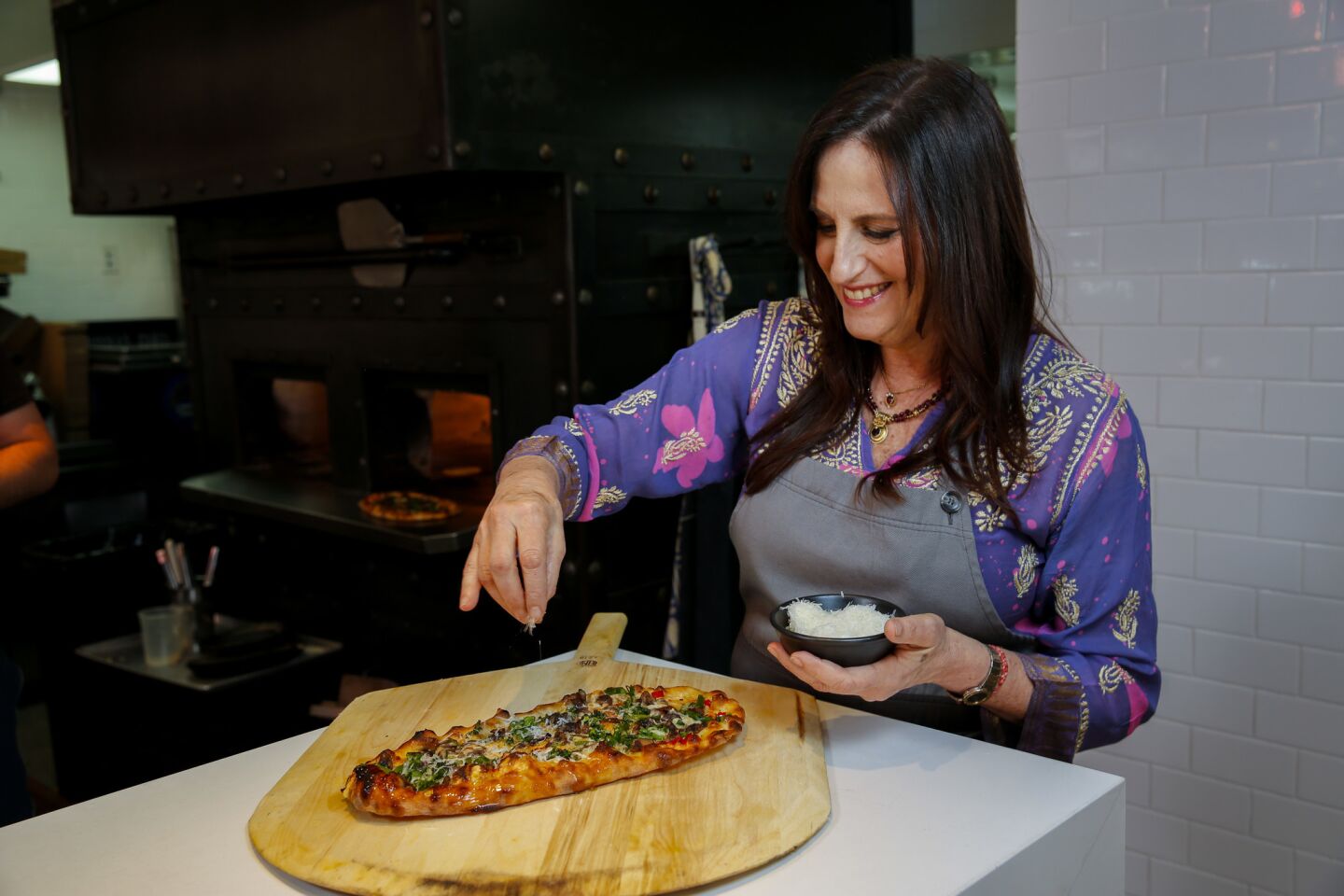 Owner and chef Akasha Richmond puts the final touches on the Thao Farms broccolini and mushroom pizza.