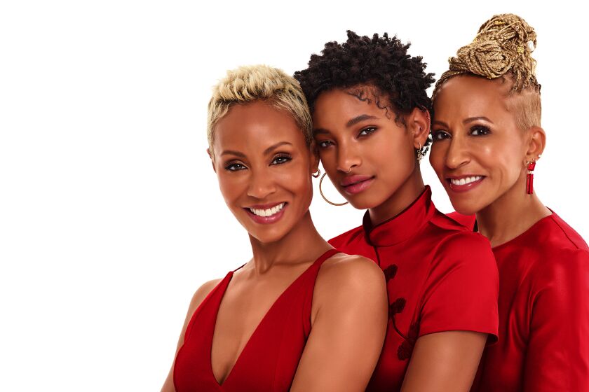 Three generations of women posing together in matching red outfits against a white background