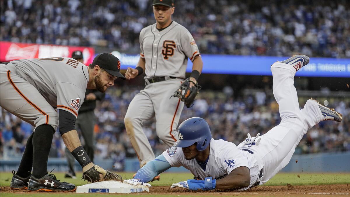 Ddogers right fielder Yasiel Puig slides safely back into first base before Giants first baseman Brandon Belt applies the tag in the fourth inning.