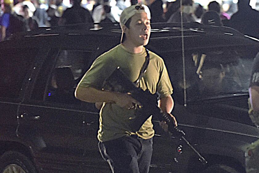 FILE - In this Tuesday, Aug. 25, 2020, file photo, Kyle Rittenhouse carries a weapon as he walks along Sheridan Road in Kenosha, Wis., during a night of unrest following the weekend police shooting of Jacob Blake. In a document filed Thursday, Oct. 8, 2020, defense attorneys say sending Rittenhouse, accused of killing two protesters days after Jacob Blake was shot by police in Kenosha, Wis., to stand trial in Wisconsin would “turn him over to the mob." (Adam Rogan/The Journal Times via AP, File)
