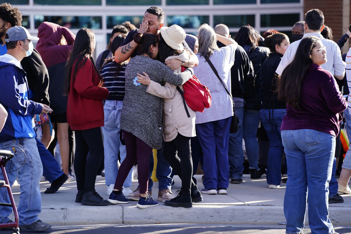 FILE - Edgar James, front center, battles with tears as he hugs his daughter, Mia, front right, and his wife, Olga Aguirre, front left, as they are reunited outside Hinkley High School in Aurora, Colo., on Friday, Nov. 19, 2021. A string of shootings involving teenagers has placed renewed attention on a long-running problem of gun violence and gangs in Aurora just outside Denver. Activists and officials say easy access to guns is contributing to the problem in Colorado's third largest city. (Philip B. Poston/Sentinel Colorado via AP,File)