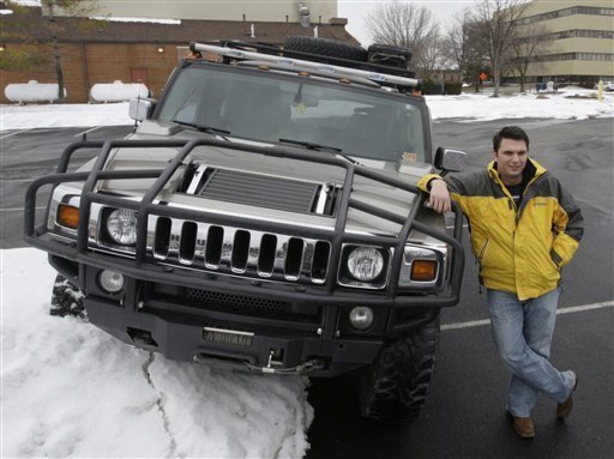Eric Sitterle poses next to his Hummer H2 that he pulled up onto a pile of snow, Thursday, Feb. 25, 2010, at a parking lot near where he works, in Cincinnati. The Hummer, the beefy, military-inspired SUV _ a macho icon for fans like Arnold Schwarzenegger and a symbol of ruin for environmentalists _ was done in by high gas prices and bad economic times. Unless a last-minute buyer steps forward, Hummer is going the way of Saturn and Pontiac. (AP Photo/Al Behrman)