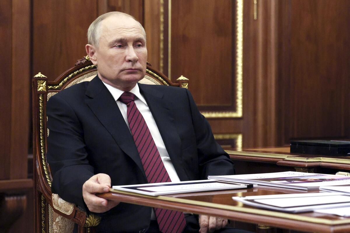 Russian President Vladimir Putin sitting at a table
