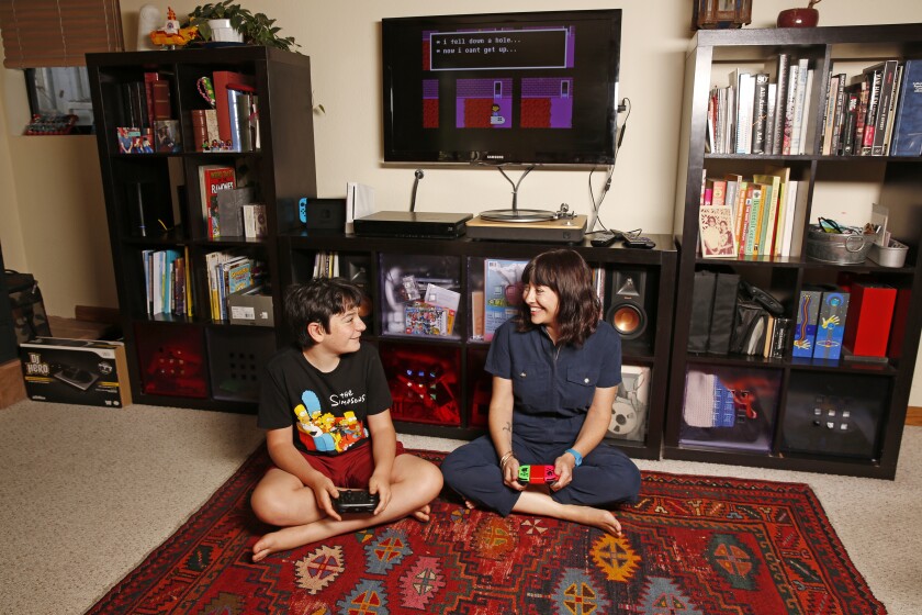 un garçon et sa mère sont assis devant un écran de jeu vidéo
