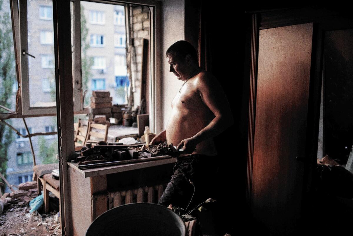 A man cleans up his damaged apartment after shelling in the Ukrainian town of Yasynuvata near the separatist stronghold of Donetsk on Aug. 12.