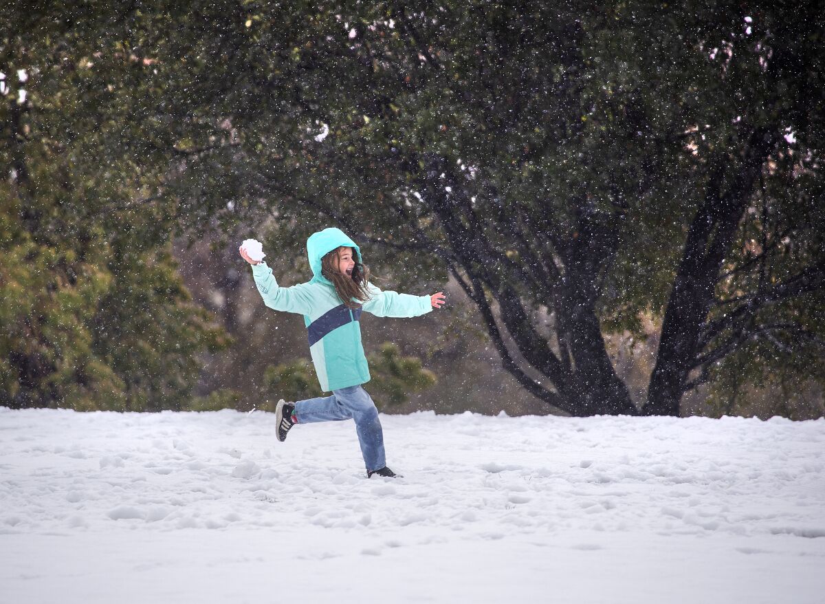 A child runs through the falling snow during a snowball fight 