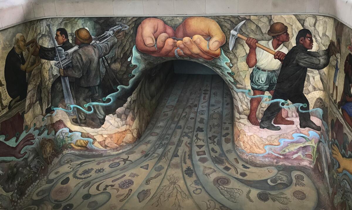 A mural depicts hands cupping water over a tunnel, with images of people on each side.