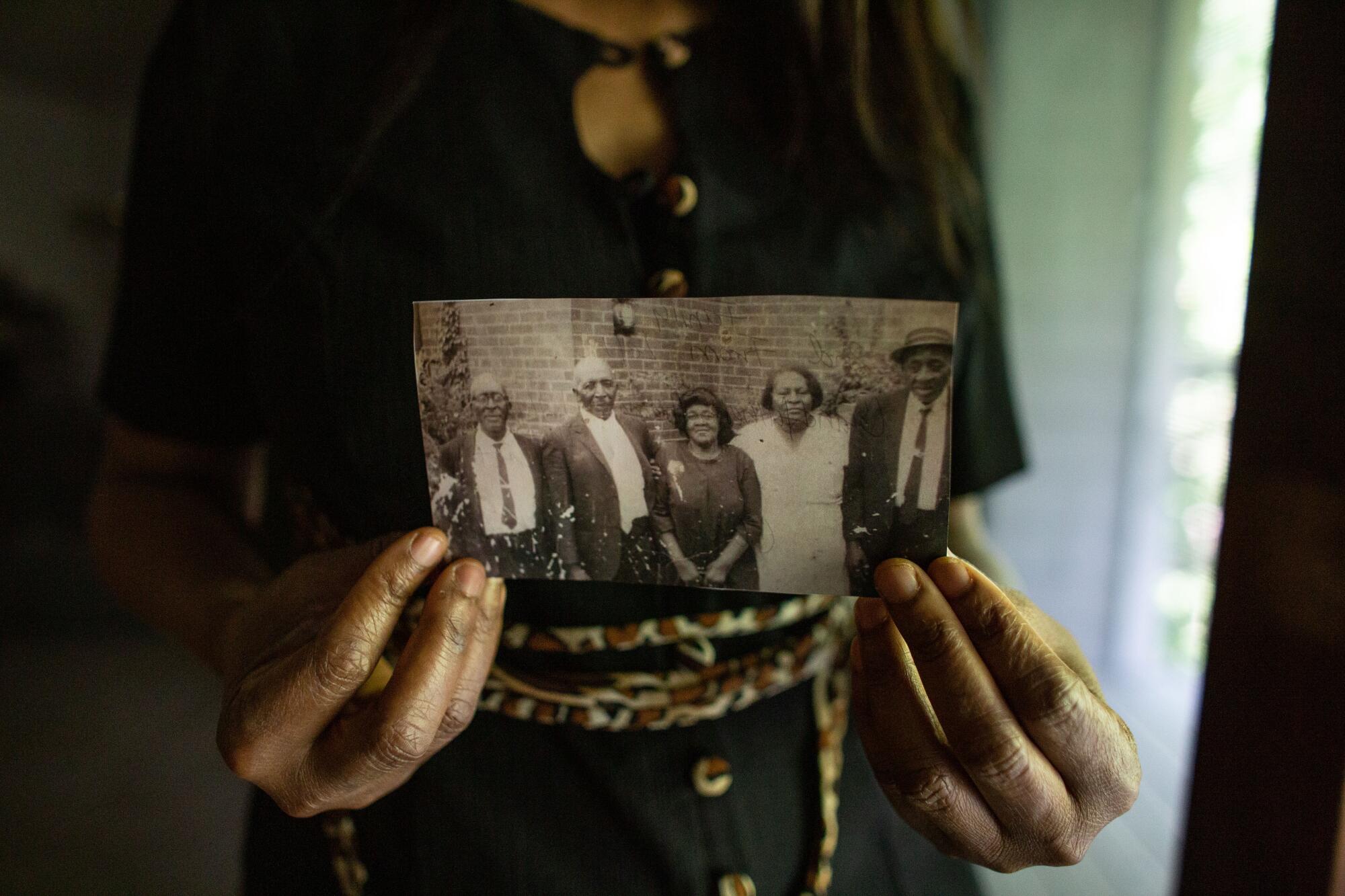 Angela Harrelson holds a photo of  George Floyd's great-grandparents and other relatives.