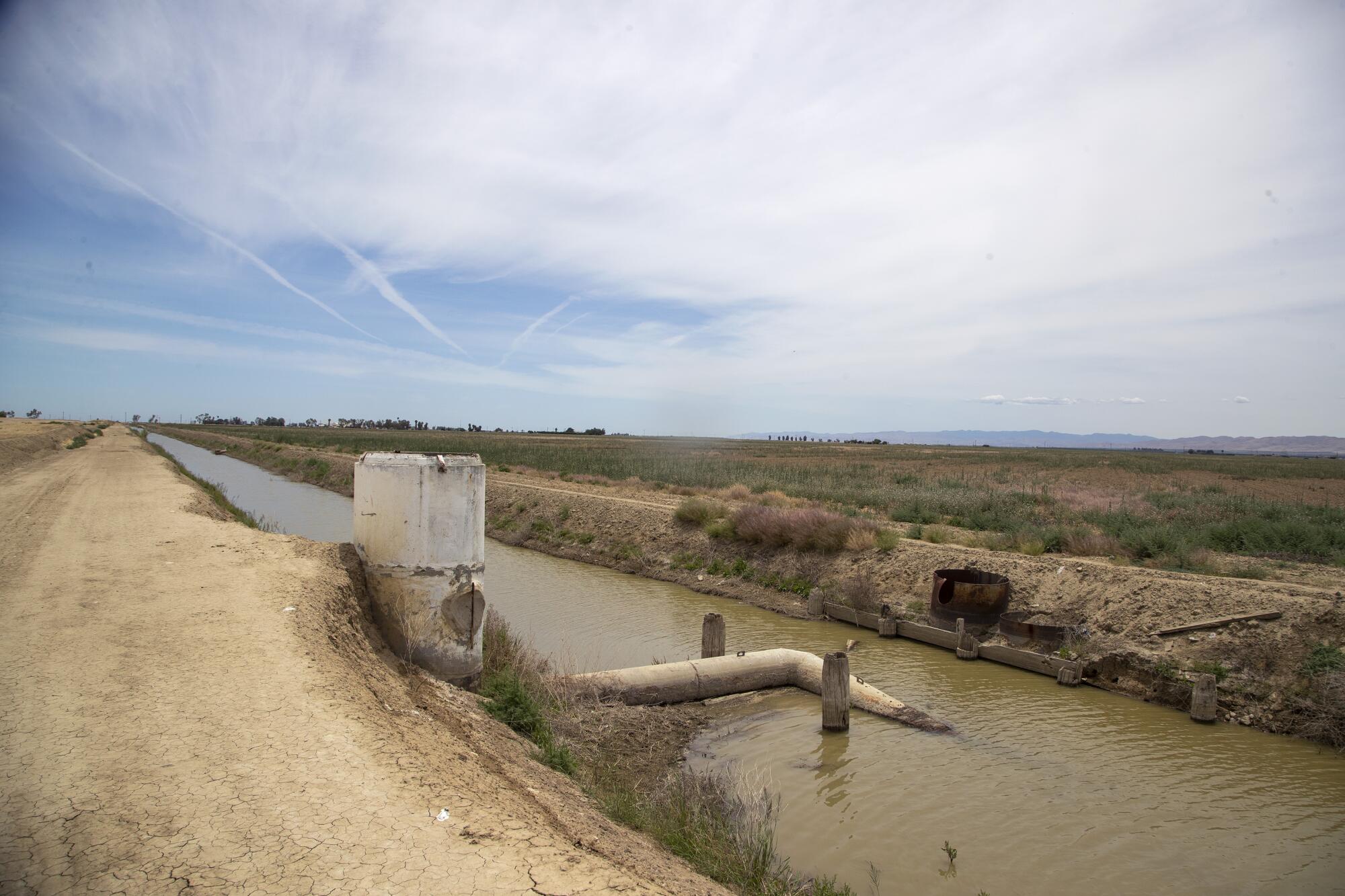 A large irrigation pipe extends into a canal.