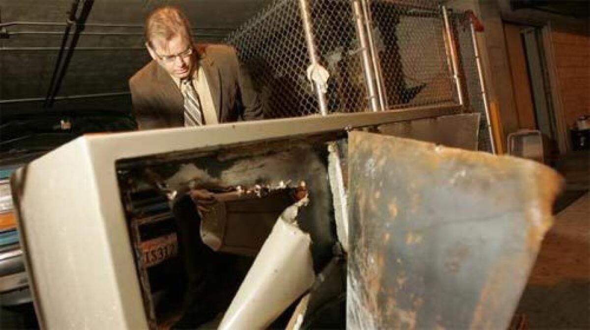 BREACHED: Andy Bales, head of the Union Rescue Mission, stands behind the safe from which a thief stole $100,000 in cash, jewelry and gift certificates early Sunday. On Monday, police said they had detained a "person of interest" in the case.