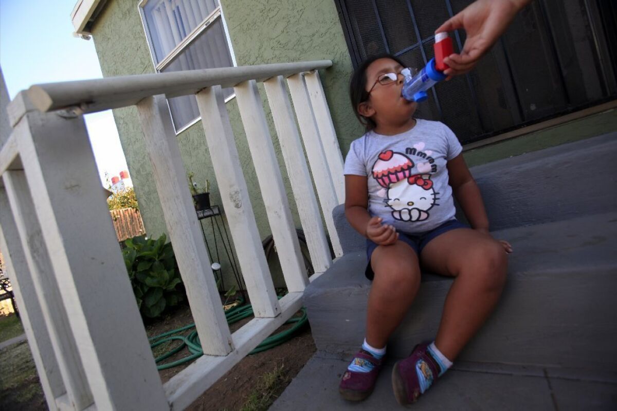 This San Diego girl with asthma gets help with her inhaler. A new study debunks the idea that childhood asthma is more common in inner cities than elsewhere in the country.