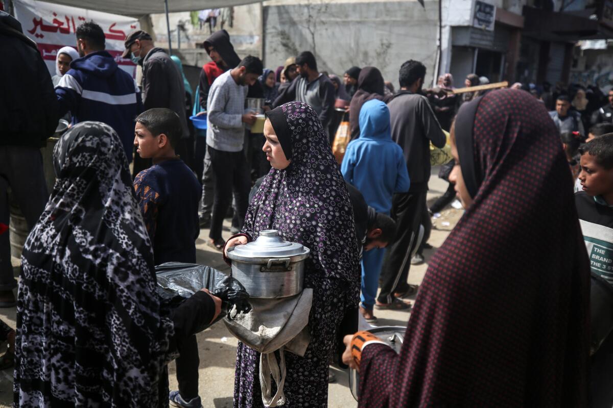 Displaced Palestinians gather to receive food at a donation point in