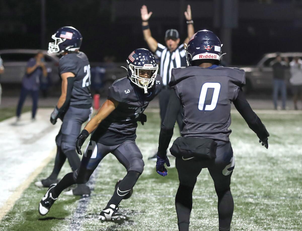 Newport Harbor's Cade Fegel (3) celebrates a touchdown with Jordan Anderson (0) during the Battle of the Bay on Friday.