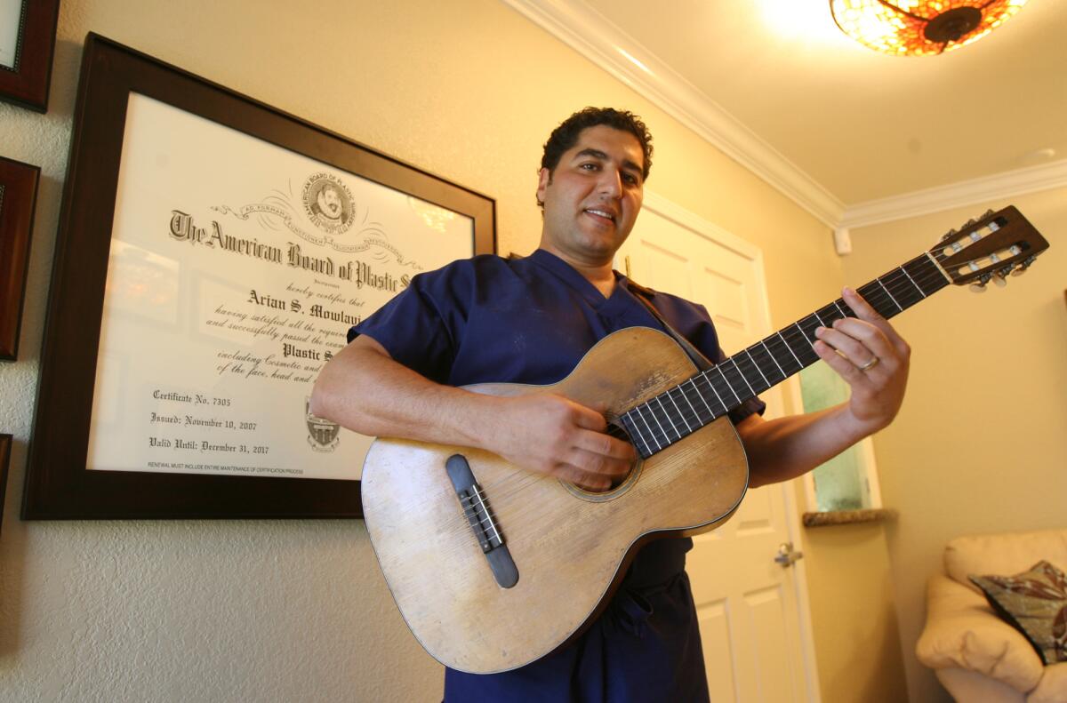 2008 photo of Dr. Arian Mowlavi playing guitar in his Laguna Beach office