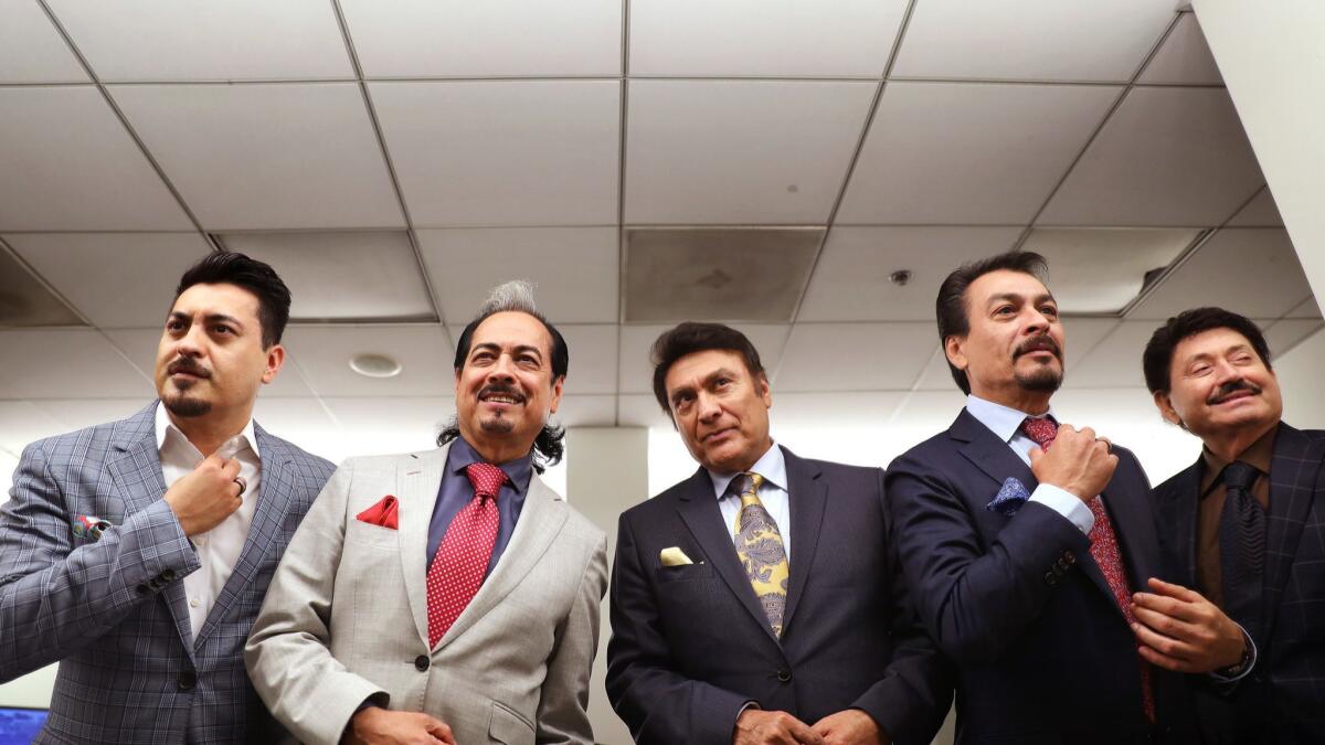 Los Tigres del Norte gussy themselves up in a green room at the Hollywood Bowl. They are, from left, Luis Hernandez, Hernán Hernandez, Jorge Hernandez, Eduardo Hernandez and Oscar Lara.