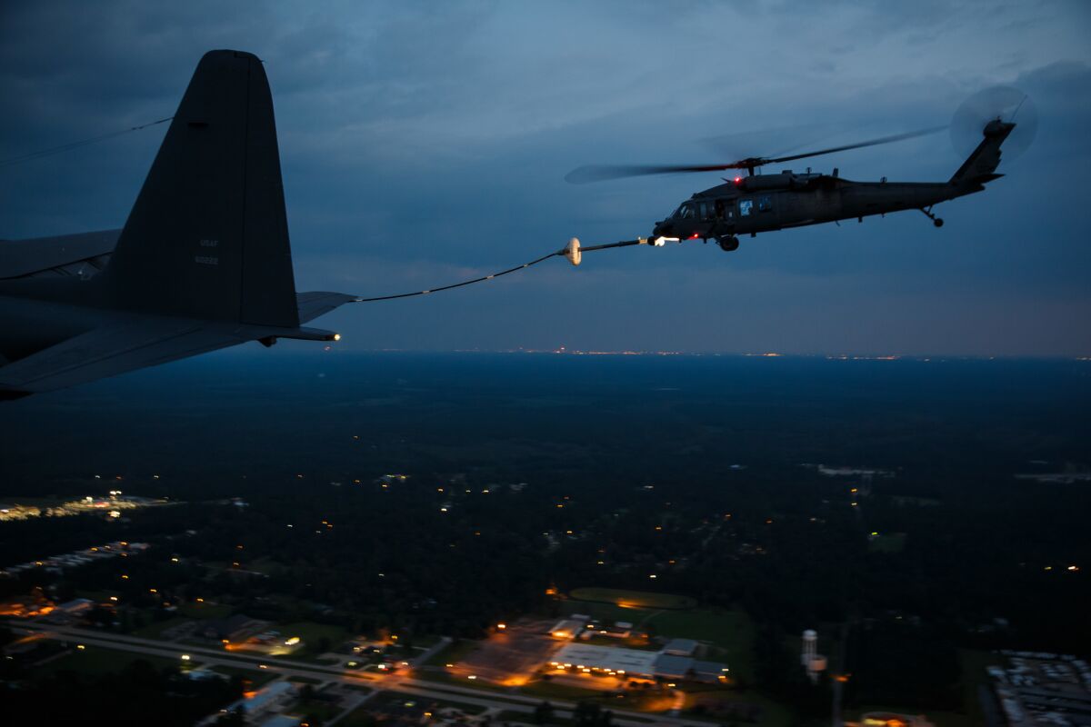 A military search and rescue helicopter refuels mid-flight before resuming nighttime missions over flood areas.