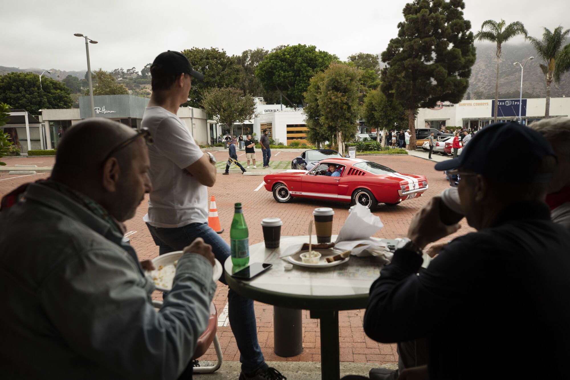 Paul Zuckerman, left, and Spike Feresten have breakfast at Malibu Country Kitchen as auto enthusiasts arrive and park. 